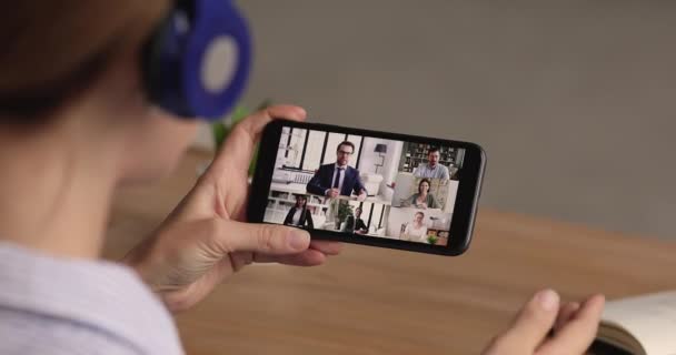 Επιχειρηματίες που συμμετέχουν σε ομαδική βιντεοδιάσκεψη, οθόνη smartphone πάνω από το γυναικείο ώμο — Αρχείο Βίντεο