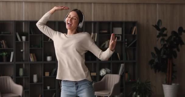 Kadın kulaklık takıyor oturma odasında dans eden müziği dinliyor — Stok video