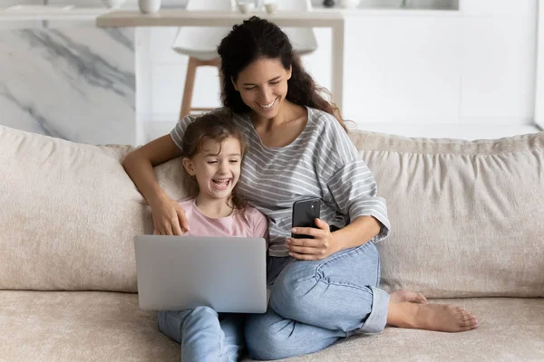 Leende spansktalande mamma och dotter använder prylar hemma — Stockfoto