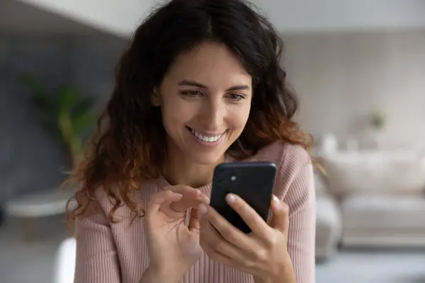 Smiling Latino woman use cellphone browsing internet — Stock Photo, Image