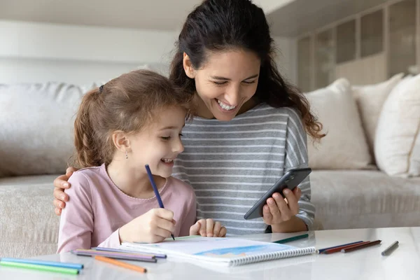 Happy Latino mom and ethnic daughter drawing together