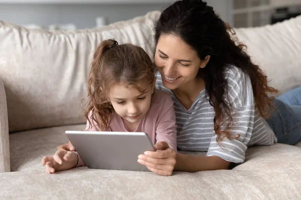 Lächelnde hispanische Mutter und Tochter verwenden Tablet zu Hause — Stockfoto