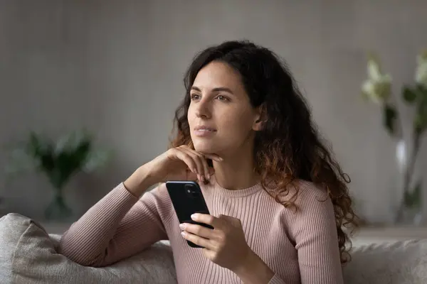 Mujer hispana pensativa usa celular relajándose en casa — Foto de Stock