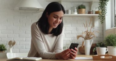 Akıllı telefon tutan Asyalı kadın mesajlarını paylaşırken gülüyor