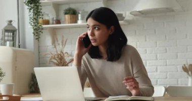 Çekici Asyalı kadın dizüstü bilgisayarla telefonda konuşuyor.