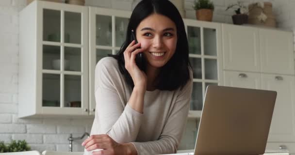 Kvinna som arbetar på bärbar dator svarar i telefon — Stockvideo