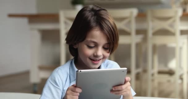 Alegre sorrindo menino relaxante em casa sozinho com tablet dispositivo — Vídeo de Stock