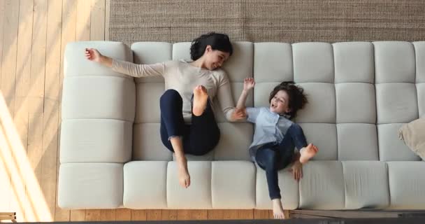 Multi mãe étnica e filho deitado no sofá desfrutar de brincadeira — Vídeo de Stock