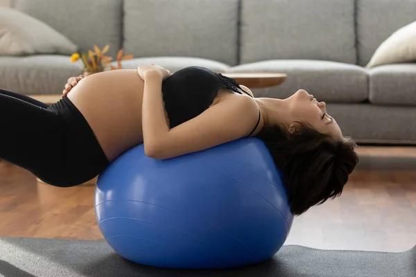 Close up pregnant woman doing exercises with fit ball