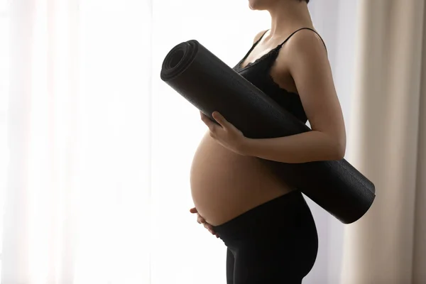 Close up cropped pregnant woman in sportswear holding yoga mat — Stock Photo, Image