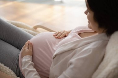 Karnına dokunan hamile bir kadın bebek bekliyor.