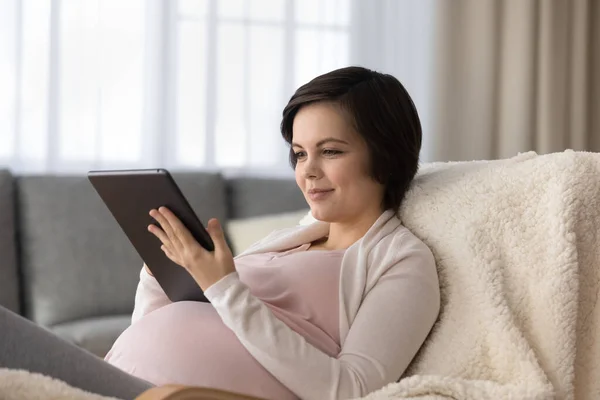 Krásná těhotná žena pomocí tablet, relaxační s gadget doma — Stock fotografie