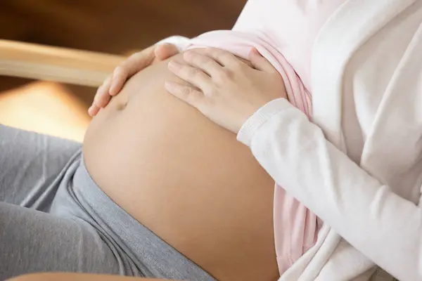 Крупный план беременной женщины, трогающей живот, ожидающей ребенка — стоковое фото