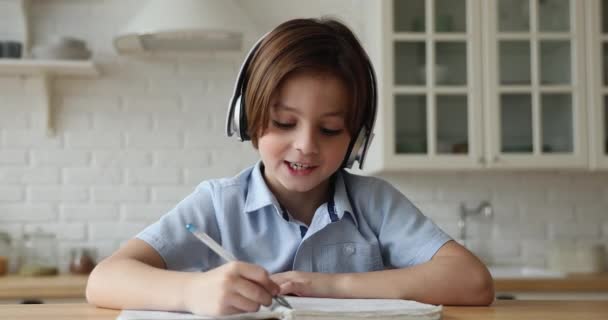 Досить маленький хлопчик носить навушники, спілкується з онлайн-репетитором — стокове відео