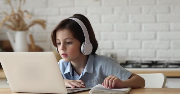 小さな男の子はビデオコールを介して数学の家庭教師にヘッドフォンの連絡先を着用 — ストック動画