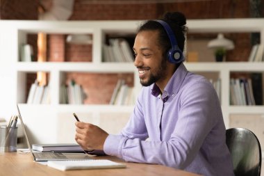 Gülümseyen Afrikalı etnik kökenli genç adam çevrimiçi eğitim konferansını izliyor.