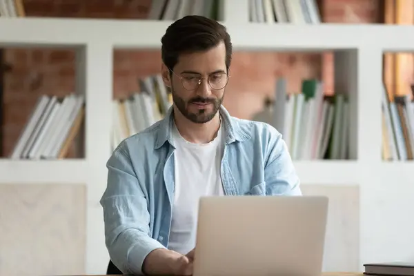 Concentrado jovem gerente masculino em óculos que trabalham no computador. — Fotografia de Stock