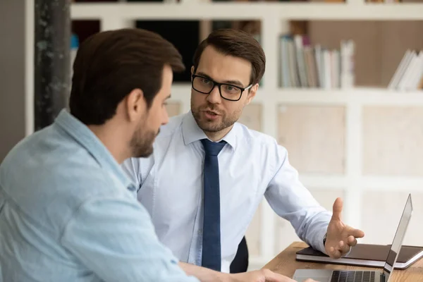 Skilled leader helping young male colleague in office. — Stock Photo, Image