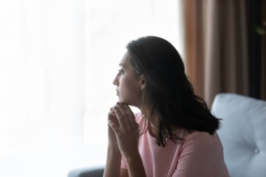 Uzaktan bakan mutsuz, düşünceli bir kadının yan görüntüsü