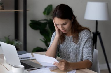 Mektupta beklenmeyen kötü haberleri okuyan mutsuz bir kadın.