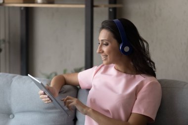 Tablet kullanan, kulaklıklı gülümseyen Arap kadının profili