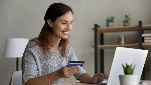 Uśmiechnięta kobieta z kartą kredytową, korzystająca z laptopa, płacąca online — Zdjęcie stockowe