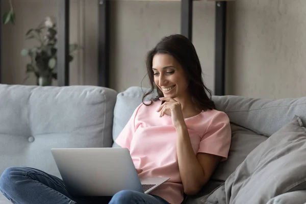 Smiling Arabian woman sitting on couch with laptop on laps — Stock Photo, Image