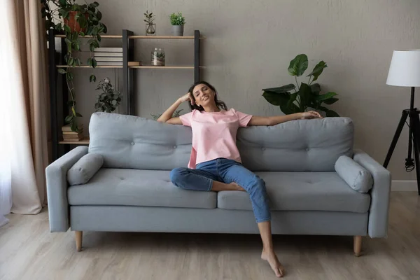 Femme arabe souriante pleine longueur se détendre sur le canapé à la maison — Photo