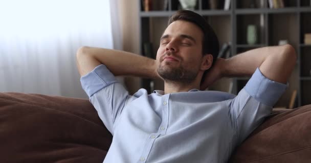 Спокійний чоловік поклав руки за голову нахилившись на зручний диван — стокове відео
