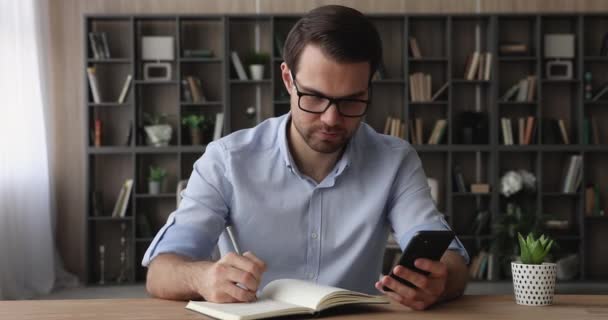 Серйозний бізнесмен тримає нотатки для запису мобільних телефонів в порядку денному — стокове відео