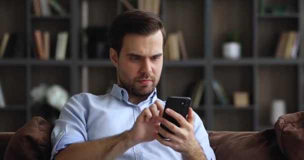 Mladý muž držící smartphone číst špatné zprávy je otrávený — Stock video