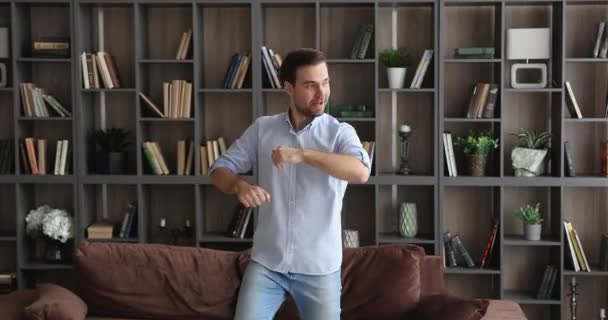 Hombre divertido bailando en sala de estar acogedora moderna — Vídeo de stock