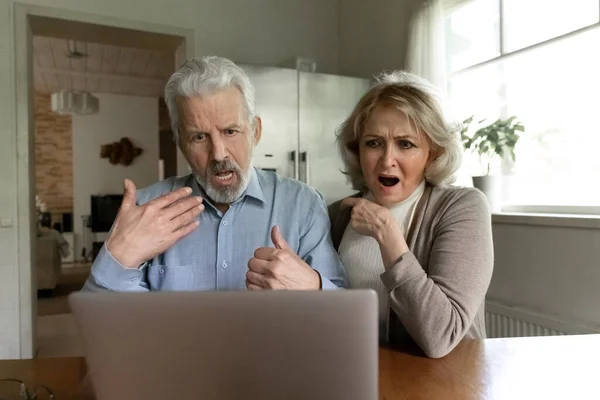 Unhappy old couple shocked by bad news on laptop