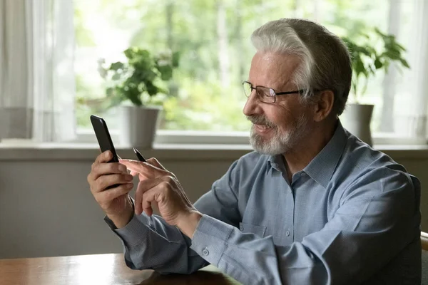 Sorrindo homem velho usar internet navegação smartphone — Fotografia de Stock