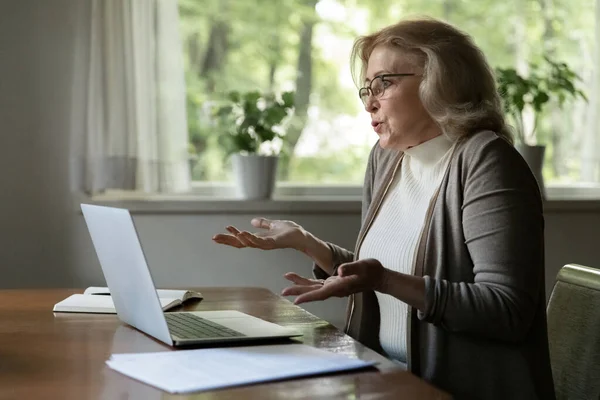 Unhappy mature woman confused with computer breakdown — Stock Photo, Image