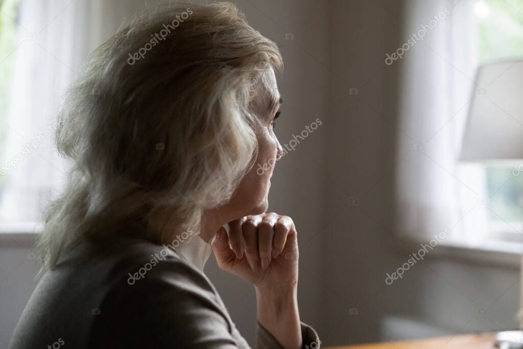 Unhappy old female look in distance feeling lonely