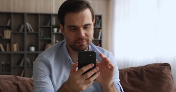 Mosolygó Y-generációs srác sms-t használ mobiltelefon — Stock videók
