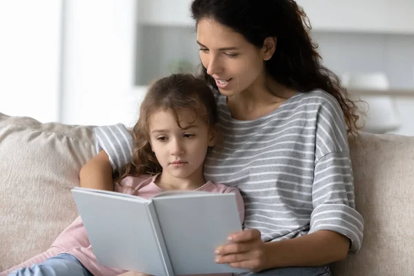 Cuidado latino mamá y adolescente hija leer libro juntos —  Fotos de Stock