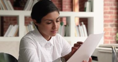 Gülümseyen genç Hintli etnik kökenli kadın finansal belge okuyor..