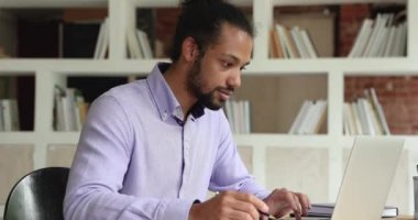 Genç, zeki, Afro-Amerikan bir adam internetten okuyor..