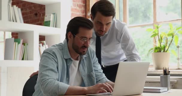 Dos empleados masculinos discutiendo proyecto de computadora en línea. — Vídeos de Stock