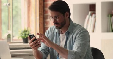 Ofiste akıllı telefon kullanan mutlu genç adam..