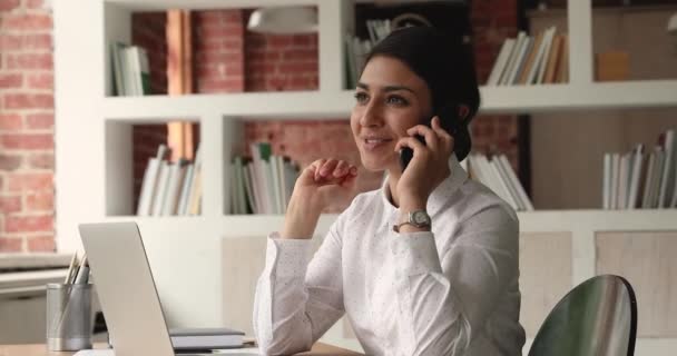 Улыбающаяся молодая индианка разговаривает по телефону в офисе. — стоковое видео
