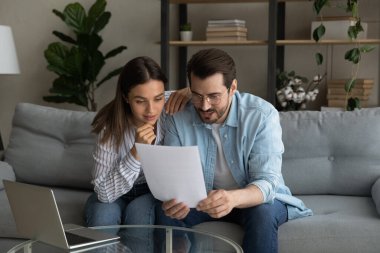 Curious interested young couple reading paper letter.