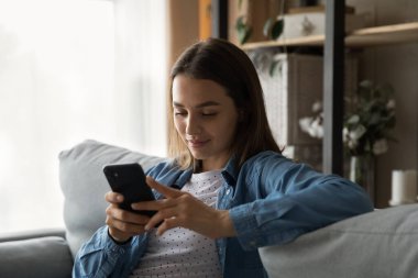 Relaxed young pretty woman using smartphone applications.