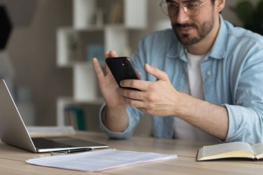 Young businessman using smartphone applications at home office.