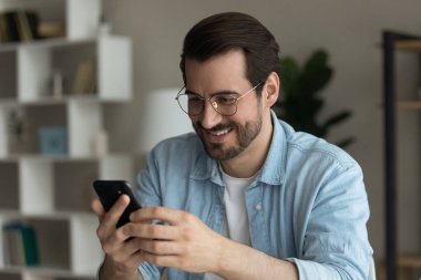 Happy young man in eyewear using cellphone gadget.