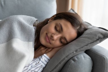 Relaxed young happy woman sleeping on comfortable sofa at home.