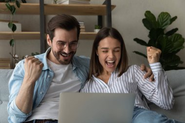 Overjoyed sincere young couple celebrating online lottery win.