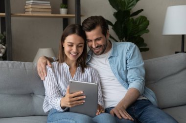 Smiling young couple using digital computer tablet.